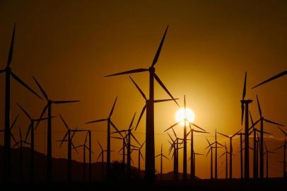 PALM SPRINGS, CA - MARCH 27: Giant wind turbines are powered by strong winds during sunset on March 27, 2013 in Palm Springs, California. According to reports, California continues to lead the nation in green technology and has the lowest greenhouse gas emissions per capita, even with a growing economy and population.   turbinas eólicas durante pôr do sol em Palm Springs, Califórnia. Segundo relatos, a Califórnia continua a liderar a nação em tecnologia verde e tem o menor emissão de gases de efeito estufa per capita, 