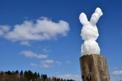 galeria - An Easter bunny built of snow stands on a stilt naer Kassel, central Germany, on April 1, 2013. Meteorologists forecast temperatures around freezing point and ongoing snowfall for the coming days in Germany. Um coelhinho da Páscoa de neve resiste a derreter em frente a casa em Kassel, região central da Alemanha