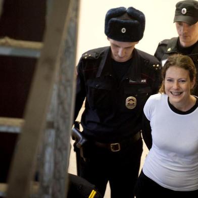 A handout picture taken on November 19, 2013 and released by Greenpeace International shows Greenpeace International activist, one of the "Arctic 30," Ana Paula Alminhana Maciel from Brazil (R), smiling while being escorted by police officers in a court in Russia's second city of Saint Petersburg. A Russian court released on bail the Brazilian Greenpeace activist, the first non-Russian to be set free from the so-called Arctic 30 detained for a protest against oil drilling, the group said today. AFP PHOTO / GREENPEACE DMITRI SHAROMOV
---EDITORS NOTE-- IMAGE AVAILABLE FOR DOWNLOAD BY EXTERNAL MEDIA FOR 14 DAYS AFTER RELEASE -- RESTRICTED TO EDITORIAL USE - MANDATORY CREDIT "AFP PHOTO / GREENPEACE /DMITRI SHAROMOV" - NO MARKETING NO ADVERTISING CAMPAIGNS - DISTRIBUTED AS A SERVICE TO CLIENTS --  NO ARCHIVE -----