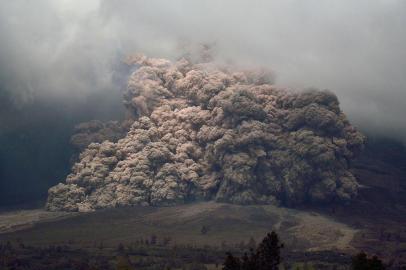 Sinabung mount spews ash to the air during an eruption near from Karo, North Sumatra on January 7, 2014. An Indonesian volcano that has erupted relentlessly for months shot volcanic ash into the air 30 times on January 4, forcing further evacuations with more than 20,000 people now displaced, an official said. AFP PHOTO / SUTANTA ADITYA