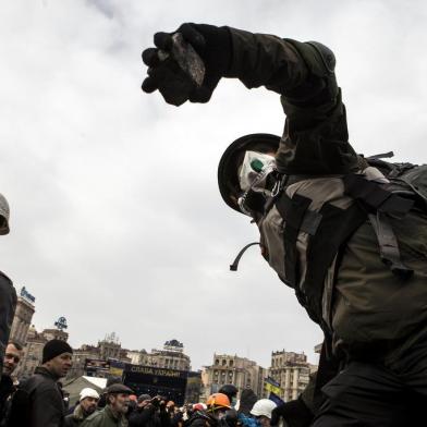 An anti-government protester prepares to throw a cobblestone at riot police during clashes on Kiev's Independence square on February 19, 2014. Protesters braced on February 19 for a fresh assault by riot police in central Kiev after a day of clashes left at least 25 people dead in the worst violence since the start of Ukraine's three-month political crisis. Ukraine's security service on February 19 announced a nationwide "anti-terrorist" operation in response to deadly anti-government protests. "The National Security Service and Ukrainian Anti-Terrorist Centre have taken the decision to conduct an anti-terrorist operation across the territory of Ukraine," security agency head Oleksandr Yakimenko said in a statement. AFP PHOTO / SANDRO MADDALENA