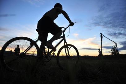  

Silhueta de criança andando de bicicleta em campo de futebol as margens da rua Kurt Meinert no bairro Panaguamirim em Joinville-SC