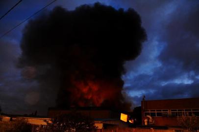 Incêndio de grandes proporções atinge fábrica de Gravataí. Além dos bombeiros do município, a corporação de Cachoeirinha auxilia no combate às chamas.