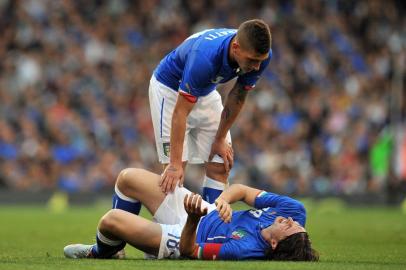 Italy's midfielder Riccardo Montolivo (floor) lies injured as Italy's midfielder Marco Verratti (top) stands over him during the international friendly football match between Italy and the Republic of Ireland at Craven Cottage in London on May 31, 2014. AFP PHOTO/GLYN KIRK