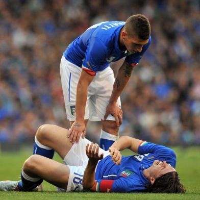 Italy's midfielder Riccardo Montolivo (floor) lies injured as Italy's midfielder Marco Verratti (top) stands over him during the international friendly football match between Italy and the Republic of Ireland at Craven Cottage in London on May 31, 2014. AFP PHOTO/GLYN KIRK