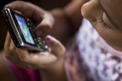  PORTO ALEGRE, RS, BRASIL, 09-10-2013: Sara Beatriz Ferreira dos Santos, 6 anos, se diverte com celular em casa, no bairro Santa Teresa. Ela e a irma Brenda Cristina Ferreira dos Santos, 11, adoram jogar no celular e no computador. (Foto: Mateus Bruxel / Diario Gaucho)Indexador: Mateus_Bruxel