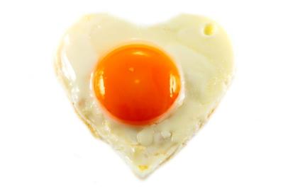 fried egg with heart shape on white background Horizontal