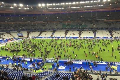 Várias explosões foram registradas nesta sexta-feira perto do Stade de France, em Paris, e um homem disparou uma arma automática de grosso calibre num restaurante da capital francesa, segundo a imprensa local. Há pelo menos 18 pessoas mortas e há reféns na casa de shows Bataclan, informou a polícia à AFP.Segundo o primeiro boletim da polícia de Paris, três pessoas foram mortas em explosões na zona do Stade de France ¿ onde França e Alemanha disputavam um amistoso assistido pelo presidente francês, François Hollande ¿ e 15 morreram no Bataclan, onde estão os reféns. A imprensa noticia também que a polícia está no local e que foram estabelecidos cordões de segurança.