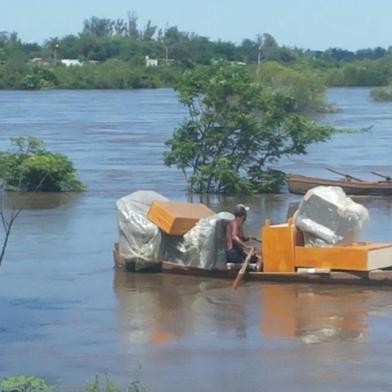 Moradores de Quaraí retiram mobília de suas casas por barco devido a cheia do Rio Uruguai