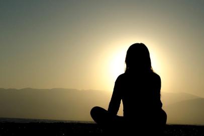 Mulher medita de frente para o sol. Saiba quais os benefícios que a meditação traz para a saúde. CADERNO VIDA. 29/04/2016.