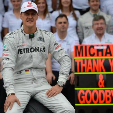 TOPSHOTS  German Formula One driver Michael Schumacher poses with the Mercedes team on November 25 , 2012 in the pits of the Interlagos racetrack in Sao Paulo, Brazil. Michael Schumacher will retire from the F-1 after the Brazilian GP.     AFP PHOTO/YASUYOSHI CHIBA