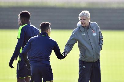 Arsenals French manager Arsene Wenger (R) shakes hands with Chilean striker Alexis Sánchez (L) during a training session ahead of their UEFA Champions League round of 16 second leg football match against Bayern Munich at Arsenals London Colney training ground on March 6, 2017.  / AFP PHOTO / GLYN KIRK