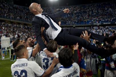 Real Madrids French head coach Zinedine Zidane is tossed by players at the end of the Spanish league football match Malaga CF vs Real Madrid at La Rosaleda stadium in Malaga on May 21, 2017.Real Madrid won their 33rd La Liga title and first for five years as Cristiano Ronaldos 40th goal of the season helped seal a 2-0 win at Malaga today. / AFP PHOTO / SERGIO CAMACHO