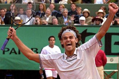 Brazilian Gustavo Kuerten celebrates after winning the men's singles final against Spanish Alex Corretja (back) 10 June 2001, at the French Tennis Open in Roland Garros, Paris. Top seed and defending champion Kuerten won the title for the third time, defeating 13th seed Alex Corretja 6-7 (3/7), 7/5, 6-2, 6-0.        AFP PHOTO/PASCAL GEORGE Fonte: AFP Fotógrafo: PASCAL GEORGE