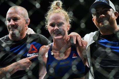 US Holly Holm (C) celebrates after knocking out Brazils Bethe Correia (not pictured) during their Ultimate Fighting Championship (UFC) womens bantamweight match at the UFC Fight Night on June 17, 2017 in Singapore. / AFP PHOTO / ROSLAN RAHMAN