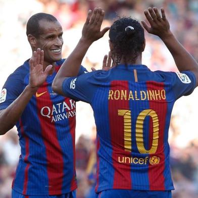 Former Barcelona's Brazilian forward Ronaldinho (R) and former Barcelona's Brazilian midfielder Rivaldo celebrate during a charity football match between Barcelona Legends vs Manchester United Legends at the Camp Nou stadium in Barcelona on June 30, 2017. / AFP PHOTO / PAU BARRENA