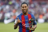 Former Barcelona's Brazilian forward Ronaldinho poses with the trophy for the best player after a charity football match between Barcelona Legends vs Manchester United Legends at the Camp Nou stadium in Barcelona on June 30, 2017. / AFP PHOTO / Pau Barrena