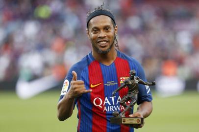 Former Barcelonas Brazilian forward Ronaldinho poses with the trophy for the best player after a charity football match between Barcelona Legends vs Manchester United Legends at the Camp Nou stadium in Barcelona on June 30, 2017. / AFP PHOTO / Pau Barrena