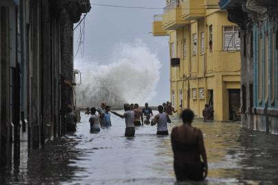 Cubans wade through a flooded street in Havana, on September 10, 2017. Deadly Hurricane Irma battered central Cuba on Saturday, knocking down power lines, uprooting trees and ripping the roofs off homes as it headed towards Florida. Authorities said they had evacuated more than a million people as a precaution, including about 4,000 in the capital.  YAMIL LAGE / AFP