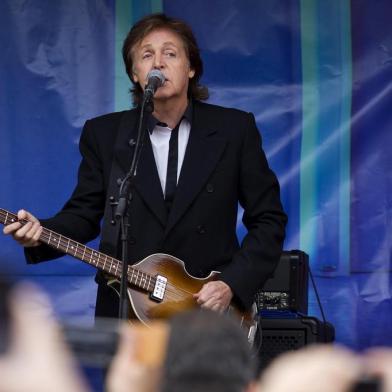 British musician Paul McCartney (C) performs during an impromptu gig in Covent Garden in London on October 18, 2013.  Paul McCartney played a surprise gig at Londons Covent Garden, drawing a crowd of hundreds as he and a band performed half a dozen songs from the back of a truck. The 71-year-old former Beatle played a colourful piano and strummed the guitar in a stunt to promote New, his first album of solo material in six years.