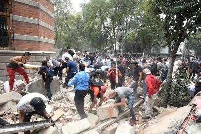 People remove debris of a damaged building after a real quake rattled Mexico City on September 19, 2017 while an earthquake drill was being held in the capital.
A powerful earthquake shook Mexico City on Tuesday, causing panic among the megalopolis' 20 million inhabitants on the 32nd anniversary of a devastating 1985 quake. The US Geological Survey put the quake's magnitude at 7.1 while Mexico's Seismological Institute said it measured 6.8 on its scale. The institute said the quake's epicenter was seven kilometers west of Chiautla de Tapia, in the neighboring state of Puebla.
 / AFP PHOTO / Alfredo ESTRELLA
