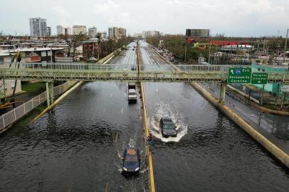 Cars drive through a flooded road in the aftermath of Hurricane Maria in San Juan, Puerto Rico, on September 21, 2017.
Puerto Rico braced for potentially calamitous flash flooding after being pummeled by Hurricane Maria which devastated the island and knocked out the entire electricity grid. The hurricane, which Puerto Rico Governor Ricardo Rossello called the most devastating storm in a century, had battered the island of 3.4 million people after roaring ashore early Wednesday with deadly winds and heavy rain.
 / AFP PHOTO / Ricardo ARDUENGO