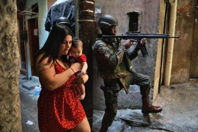  

A woman walks with her baby past a PM militarized police soldier in position and aiming his rifle in Rocinha favela in Rio de Janeiro, Brazil on September 23, 2017. 
Although shooting was reported in the early hours of Saturday in Rocinha -- for the seventh day running -- officials said that Fridays deployment of 950 soldiers to reinforce police had brought the crisis under control. / AFP PHOTO / CARL DE SOUZA

Editoria: CLJ
Local: Rio de Janeiro
Indexador: CARL DE SOUZA
Secao: crime
Fonte: AFP
Fotógrafo: STF