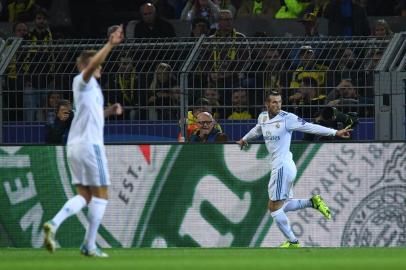 Real Madrids forward from Wales Gareth Bale (R) celebrates scoring the opening goal with his teammates during the UEFA Champions League Group H football match BVB Borussia Dortmund v Real Madrid in Dortmund, western Germany on September 26, 2017. / AFP PHOTO / Patrik STOLLARZ