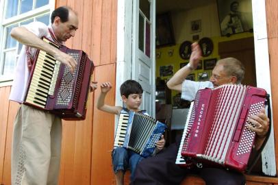  Adelar Bertussi, em sua propriedade na localidade de Criuva, São Marcos - Com o filho Gilnei e o neto Gabriel, tocando em frente de casa
