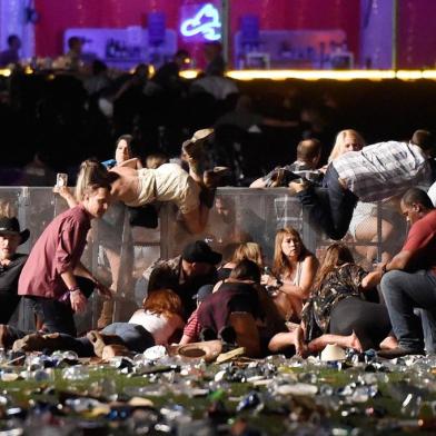 LAS VEGAS, NV - OCTOBER 01: People scramble for shelter at the Route 91 Harvest country music festival after apparent gun fire was heard on October 1, 2017 in Las Vegas, Nevada. A gunman has opened fire on a music festival in Las Vegas, leaving at least 20 people dead and more than 100 injured. Police have confirmed that one suspect has been shot. The investigation is ongoing.   David Becker/Getty Images/AFP