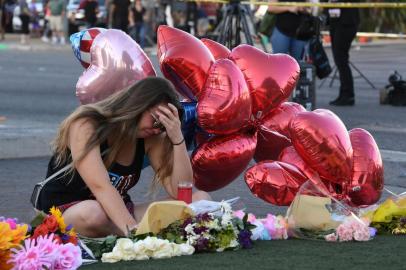 Destiny Alvers who attended the Route 91 country music festival and helped rescue her friend who was shot, reacts at a makeshift memorial on the Las Vegas Strip in Las Vegas, Nevada on October 3, 2017, after a gunman killed 59 people and wounded more than 500 others when he opened fire from a hotel window on a country music festival.
Police said the gunman, a 64-year-old local resident named as Stephen Paddock, had been killed after a SWAT team responded to reports of multiple gunfire from the 32nd floor of the Mandalay Bay, a hotel-casino next to the concert venue. / AFP PHOTO / Mark RALSTON