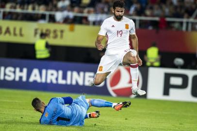 Spains Diego Kosta (L) jumps over  with Macedonias goalkeeper Stole Dimitrievski during  the FIFA World Cup 2018 qualification football match between Macedonia and Spain at  the Philip II Arena in Skopje, on June 11, 2017. / AFP PHOTO / Robert ATANASOVSKI