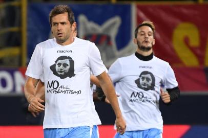 Lazios midfielder from Bosnia-Herzegovina Senad Lulic (L) wears a t-shirt showing an image of holocaust victim Anne Frank, during the warm up prior the Italian Serie A football match Bologna vs Lazio on October 25, 2017 at the Renato-DallAra stadium in Bologna. Emotions were still running high in Italy, days after Lazio fans posted anti-semitic photos of Anne Frank in a Roma jersey in the stands of the Stadio Olimpico.
The Italian football federation announced that there will be a minutes reflection on the Holocaust before every match and a passage read from The Diary of Anne Frank. At the same time referees and captains will hand out copies of the diary and Italian Jewish writer Primo Levis memoir If This Is A Man.
 / AFP PHOTO / Gianni SCHICCHI