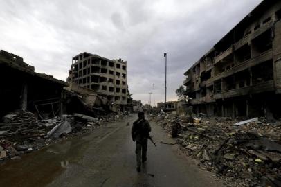 A picture taken on October 28, 2017, shows a fighter of the Syrian Democratic Forces (SDF) walking through an empty rubble-filled street surrounded by damaged buildings in the Syrian city of Raqa.
The US-backed SDF took full control of Raqa on October 17, wrapping up an operation that lasted more than four months to capture a city that had been the inner sanctum of ISs now moribund caliphate.
Hundreds of thousands of people fled the city since 2014 and by the time the SDF retook it, Raqa had become a ghost town of collapsed buildings. / AFP PHOTO / Delil souleiman