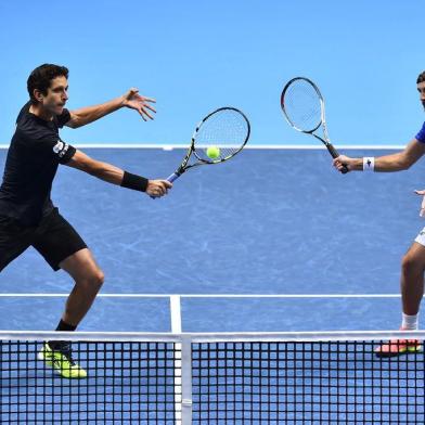 Brazils Marcelo Melo (L) returns as his partner Polands Lukasz Kubot (R) stands ready against Croatias Ivan Dodig and Spains Marcel Granollers during their mens doubles match on day two of the ATP World Tour Finals tennis tournament at the O2 Arena in London on November 13, 2017. / AFP PHOTO / Glyn KIRK