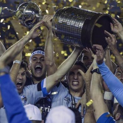  Brazils Gremio footballers celebrate with the trophy after winning the Copa Libertadores 2017 final football match against Argentinas Lanus at Lanus stadium in Lanus, Buenos Aires, Argentina, on November 29, 2017. Gremio won 2-1 to become the champion of the Copa Libertadores 2017. / AFP PHOTO / JUAN MABROMATAEditoria: SPOLocal: Buenos AiresIndexador: JUAN MABROMATASecao: soccerFonte: AFPFotógrafo: STF