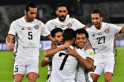 Al-Jaziras Emirati forward Ali Mabkhout (C, front) embraces his teammates Moroccan Mbark Boussoufa (C-L, behind) and Brazillian Romarinho (C-R, behind), as they celebrate after him scoring a goal against Urawa Reds during their FIFA Club World Cup quarter-final match at Zayed Sports City Stadium in the Emirati capital Abu Dhabi on December 9, 2017. / AFP PHOTO / GIUSEPPE CACACE