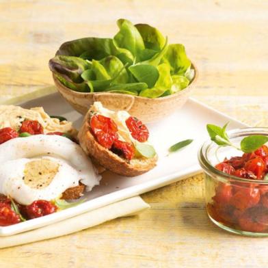 Salada de folhas com pão, homus, tomates assados e ovos pochê