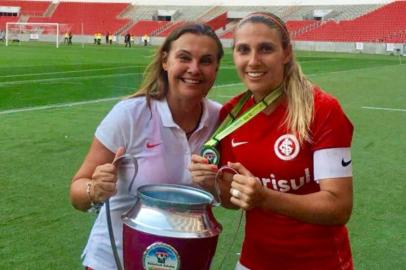 Gabi (de vermelho), volante da equipe feminina do Inter, sai de campo com a irmã, Duda, hoje coordenadora do futebol feminino.As duas exibem a taça de campeã gaúcha 2017. 