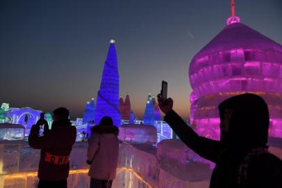 People visit the Harbin Ice and Snow World, part of the annual Harbin Ice and Snow Sculpture Festival in Harbin in Chinas northeast Heilongjiang province on January 4, 2018.The festival, which attracts hundreds of thousands of visitors annually, officially opens on January 5. / AFP PHOTO / GREG BAKER