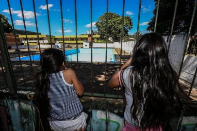  PORTO ALEGRE, RS, BRASIL - 2018.01.07 - Pela primeira vez, piscina do Centro da Comunidade Parque Madepinho (CECOPAM), no Bairro Cavalhada, em Porto Alegre, está fechada para a comunidade. Na foto: As irmãs Paloma e Poliana Paes olham a piscina por uma fresta do muro do Centro. (Foto: ANDRÉ ÁVILA/ Agência RBS)Indexador: Andre Avila