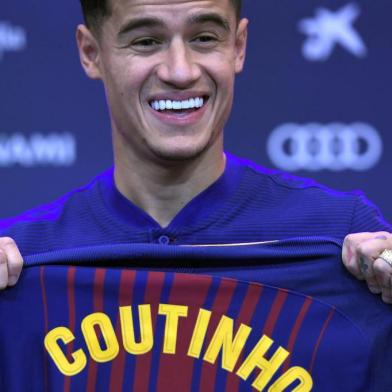 Barcelonas new Brazilian midfielder Philippe Coutinho shows his new jersey before holding a press conference in Barcelona on January 8, 2018. Philippe Coutinho officially joined Barcelona today, completing a move from Liverpool thought to be worth 160 million euros ($192 million), making it the third richest transfer in history. / AFP PHOTO / LLUIS GENE