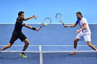 Brazils Marcelo Melo (L) returns as his partner Polands Lukasz Kubot (R) stands ready against Croatias Ivan Dodig and Spains Marcel Granollers during their mens doubles match on day two of the ATP World Tour Finals tennis tournament at the O2 Arena in London on November 13, 2017. / AFP PHOTO / Glyn KIRK