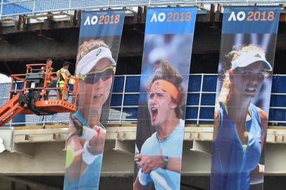 Workmen put the final touches to banners covering construction work at a building in Melbourne Park ahead of the Australian Open tennis tournament in Melbourne on January 12, 2018. / AFP PHOTO / PAUL CROCK / IMAGE RESTRICTED TO EDITORIAL USE - STRICTLY NO COMMERCIAL USE