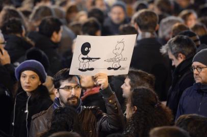 A man holds a drawing during a gathering at the Place de la Republique (Republic square) in Paris, on January 7, 2015, following an attack by unknown gunmen on the offices of the satirical weekly, Charlie Hebdo. Frances Muslim leadership sharply condemned the shooting at the Paris satirical weekly that left at least 12 people dead as a barbaric attack and an assault on press freedom and democracy. AFP PHOTO / ERIC FEFERBERG
