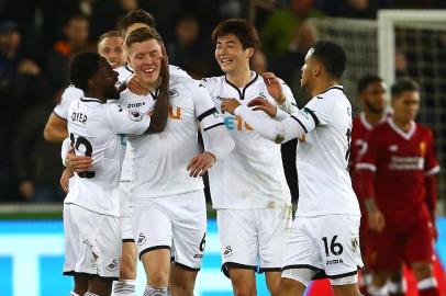 Swansea Citys English defender Alfie Mawson (C) celebrates with teammates after scoring the opening goal of the English Premier League football match between Swansea City and Liverpool at The Liberty Stadium in Swansea, south Wales on January 22, 2018. / AFP PHOTO / Geoff CADDICK / RESTRICTED TO EDITORIAL USE. No use with unauthorized audio, video, data, fixture lists, club/league logos or live services. Online in-match use limited to 75 images, no video emulation. No use in betting, games or single club/league/player publications.  / 