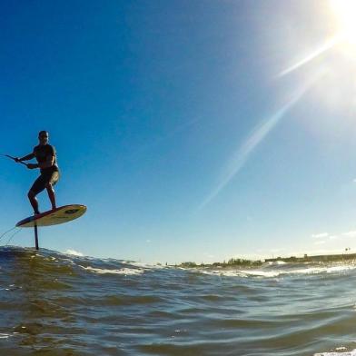  ATLÂNTIDA, RS, BRASIL, 21-01-2018. Elias Seadi, instrutor de kitesurf, trouxe uma nova modalidade pro surfe no Brasil. Foilboard, uma modalidade que utiliza uma peça diferente para levantar a prancha em pleno ar durante o passeio. O hidrofólio é um equipamento que funciona como uma quilha e que, além de um cano que parece flutuar sozinho, possui uma base que se assemelha às asas de um avião. Quando certas velocidades são atingidas, a peça diminui o atrito da prancha com a água e, sustentando o surfista, permite manobras radicais e uma sensação única. (FOTO: ANDERSON FETTER/AGÊNCIA RBS)