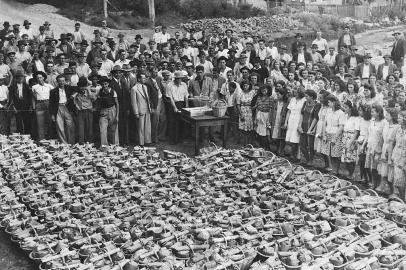 Distribuição de ranchos no pátio do Lanifício Gianella em dezembro de 1941.Na foto, ao centro, os irmãos Doviglio Gianella e Remo Gianella, filhos de Matteo Gianella e Ermelinda Viero Gianella. Na gaveta da mesa, as fichas com os nomes dos operários, que iam sendo chamados, um por um, para receber a cesta. 