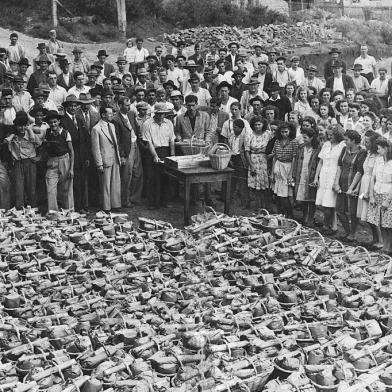 Distribuição de ranchos no pátio do Lanifício Gianella em dezembro de 1941.Na foto, ao centro, os irmãos Doviglio Gianella e Remo Gianella, filhos de Matteo Gianella e Ermelinda Viero Gianella. Na gaveta da mesa, as fichas com os nomes dos operários, que iam sendo chamados, um por um, para receber a cesta. 