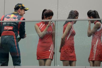 Winner Red Bull-Renault driver Sebastian Vettel of Germany (L) sprays champagne at Indian grid girls after his victory at the Formula One Indian Grand Prix at The Buddh International circuit in Greater Noida, on the outskirts of New Delhi on October 28, 2012. AFP PHOTO/ Punit PARANJPE